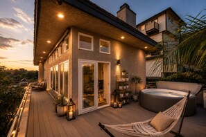 Een modern huis met een terras, een jacuzzi en een hangmat.