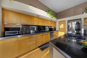 A modern kitchen with wooden cabinets, stainless steel appliances, and a black granite countertop. - Panoramic Estate As Seen on 90 Day Fiancé (La Mesa)