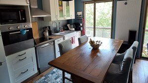A modern kitchen with a central island, built-in appliances, and a large window. - Canal & Garonne Atmosphere – Live Like a True Toulousain (Toulouse)