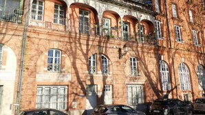 A multi-story building with arched windows and balconies, featuring a brick facade and a clear blue sky. - Canal & Garonne Atmosphere – Live Like a True Toulousain (Toulouse)