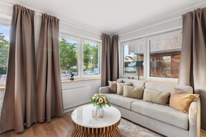 Ein modernes Wohnzimmer mit einer Couch, einem runden Couchtisch und Vorhängen.
