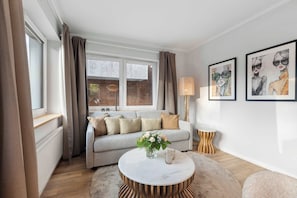Ein Wohnzimmer mit einer Couch, einem runden Couchtisch, einer Lampe und Kunstwerken an der Wand.