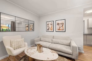 Un saló modern amb un sofà, un butaca i una taula de centre rodona.