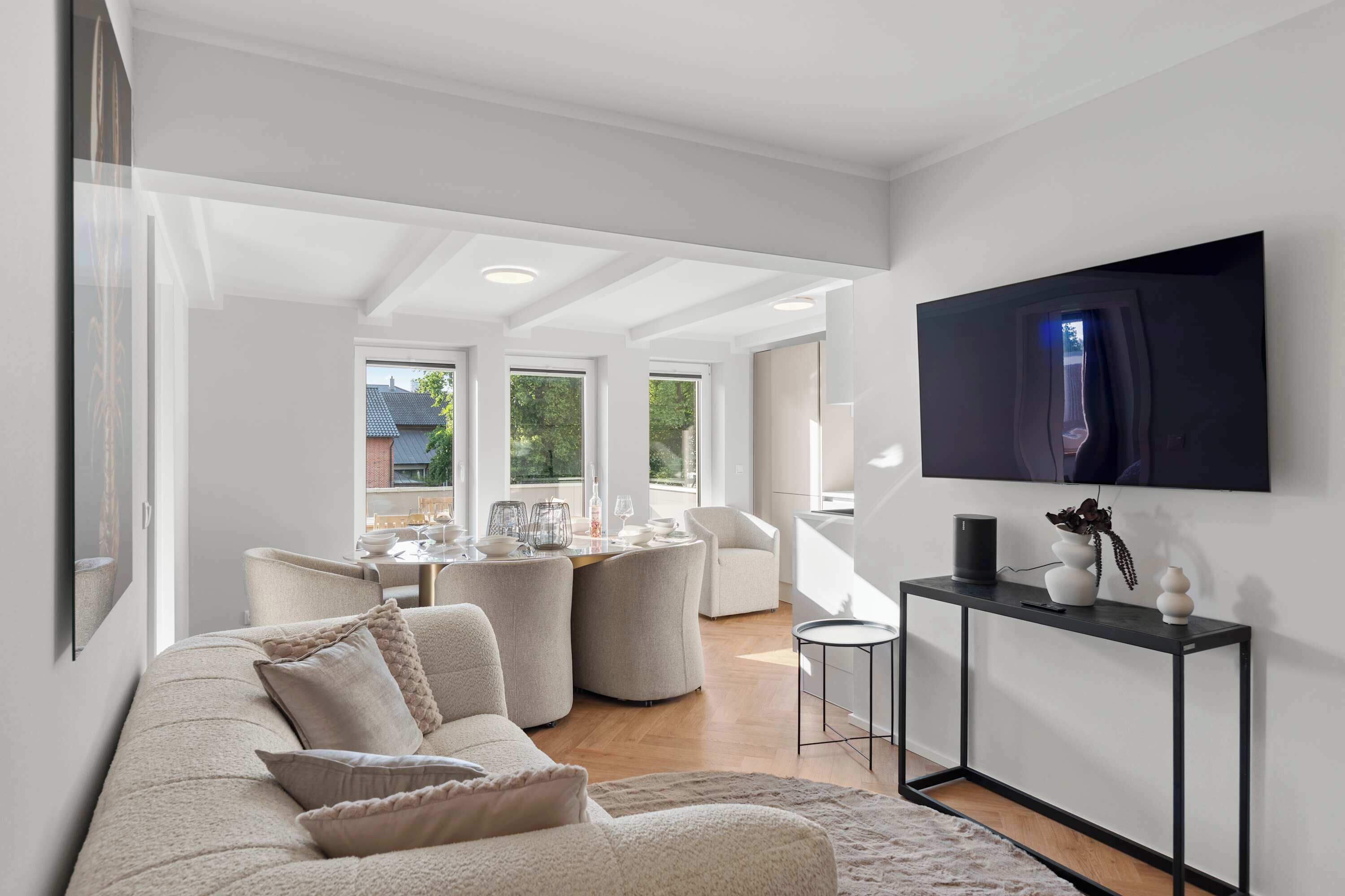 En moderne stue med sofa, spiseplads og et fjernsyn monteret på væggen.