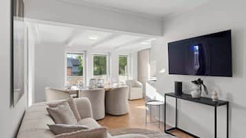 En moderne stue med sofa, spiseplads og et fjernsyn monteret på væggen.