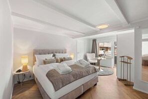 Una habitación de hotel moderna con una cama grande, mesitas de noche, un escritorio y vistas a la ciudad.