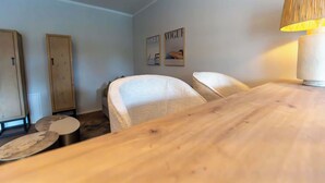 Ein Zimmer mit Holztisch, zwei Stühlen, einer Lampe und einem Kleiderschrank.