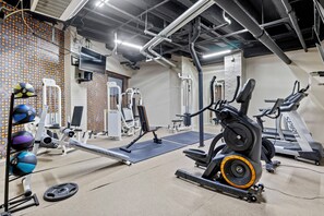 Ein Fitnessstudio mit verschiedenen Trainingsgeräten, darunter Laufbänder, Kraftgeräte und Kurzhanteln.