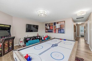 Una habitación con una mesa de fútbol, televisión y un sofá.