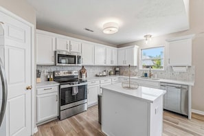 A modern kitchen with white cabinetry, stainless steel appliances, and a central island.