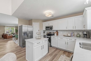 A modern kitchen with white cabinets, stainless steel appliances, and a central island.