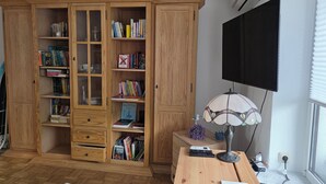 Una habitación con un armario de madera, un escritorio con lámpara, un televisor y un aire acondicionado.