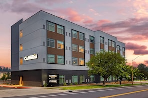 A modern multi-story hotel with a flat facade, large windows, and a prominent signage for 'CAMBRIA hotel'.