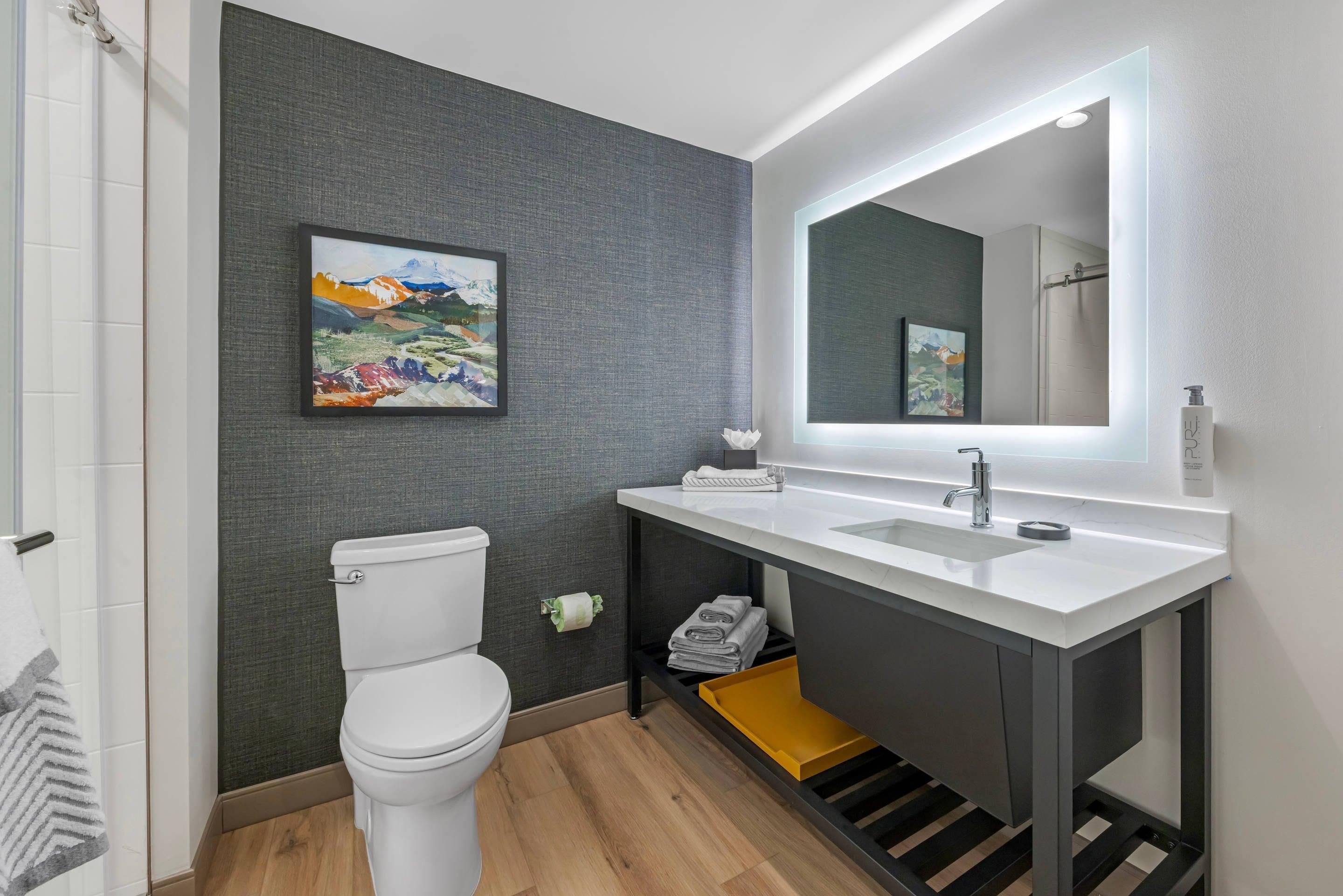 Ein modernes Badezimmer mit Toilette, Waschbecken mit Spiegel und Duschbereich.