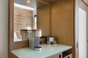 A modern kitchenette with a built-in coffee maker, a mirror, and a small table with glasses. - Cambria Hotel Bend - Mt. Bachelor (Bend)
