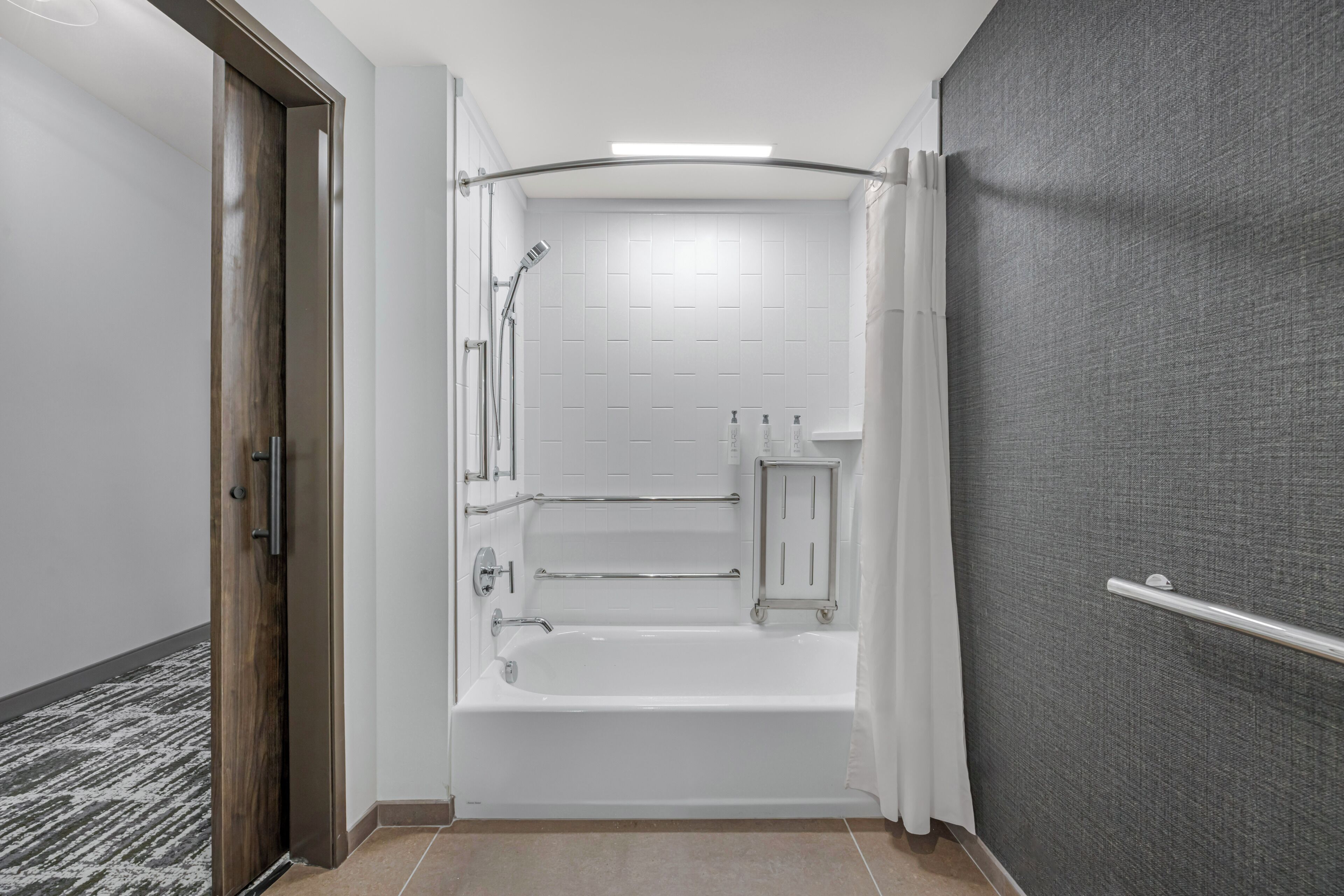 Un baño moderno con bañera, ducha y barras de apoyo.