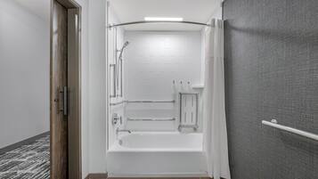 Un baño moderno con bañera, ducha y barras de apoyo.