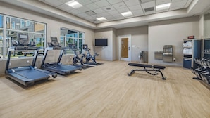 A fitness center with treadmills, stationary bikes, and a bench.