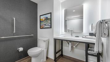 Un baño moderno con inodoro, lavamanos, espejo y zona de ducha.