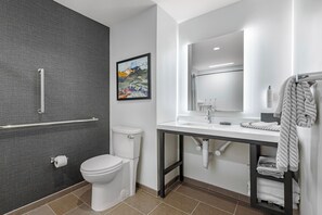 Un baño moderno con inodoro, lavamanos, espejo y zona de ducha.
