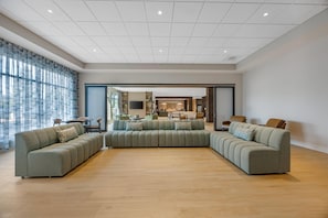 Un amplio salón con un sofá seccional grande, una zona de comedor y una cocina al fondo.