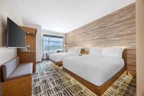 Habitación de hotel moderna con una cama grande, zona de estar, televisor de pantalla plana y vistas al exterior.