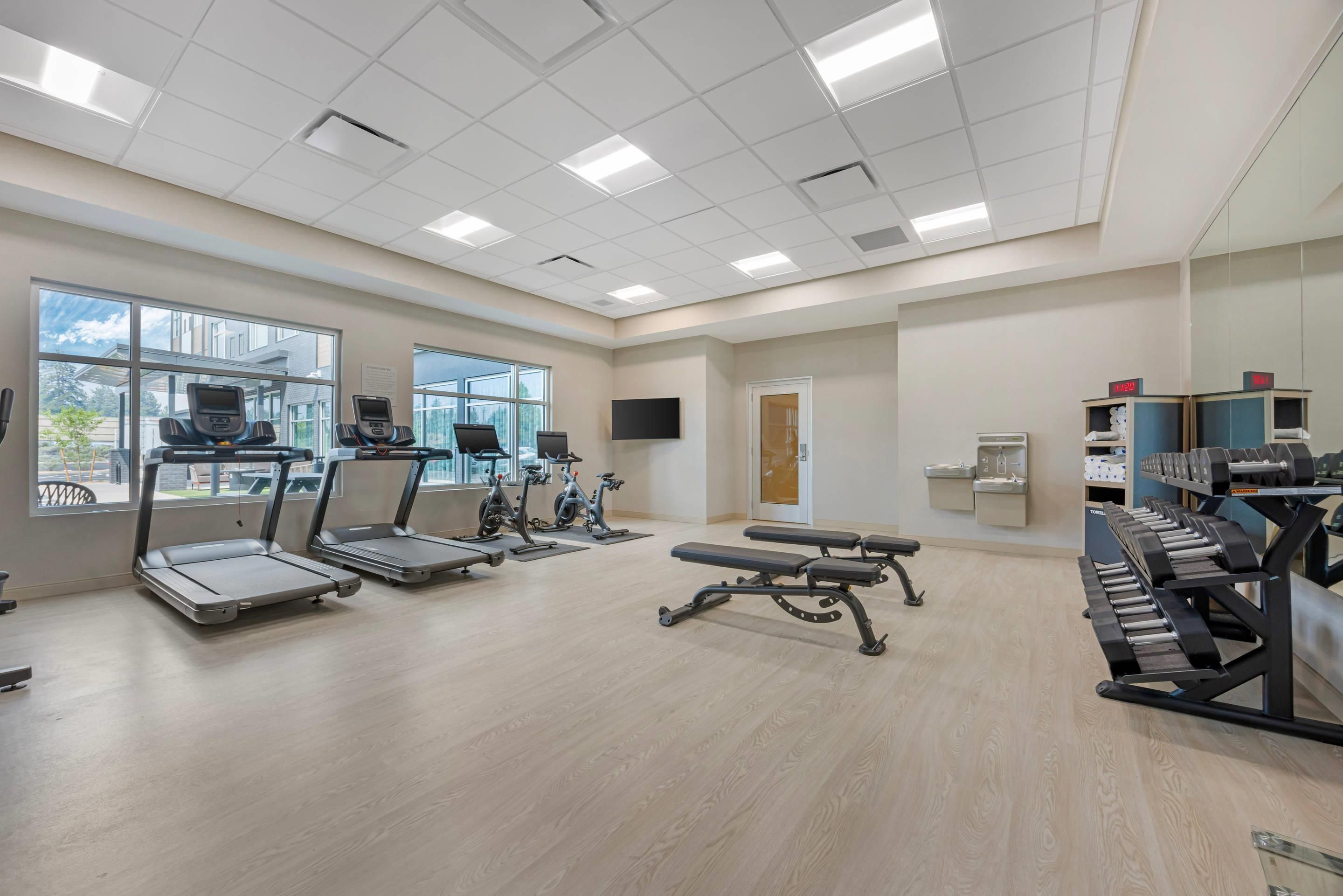 A gym with treadmills, stationary bikes, a bench press, and a weight rack.