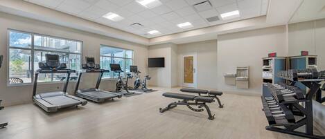 A gym with treadmills, stationary bikes, a bench press, and a weight rack.