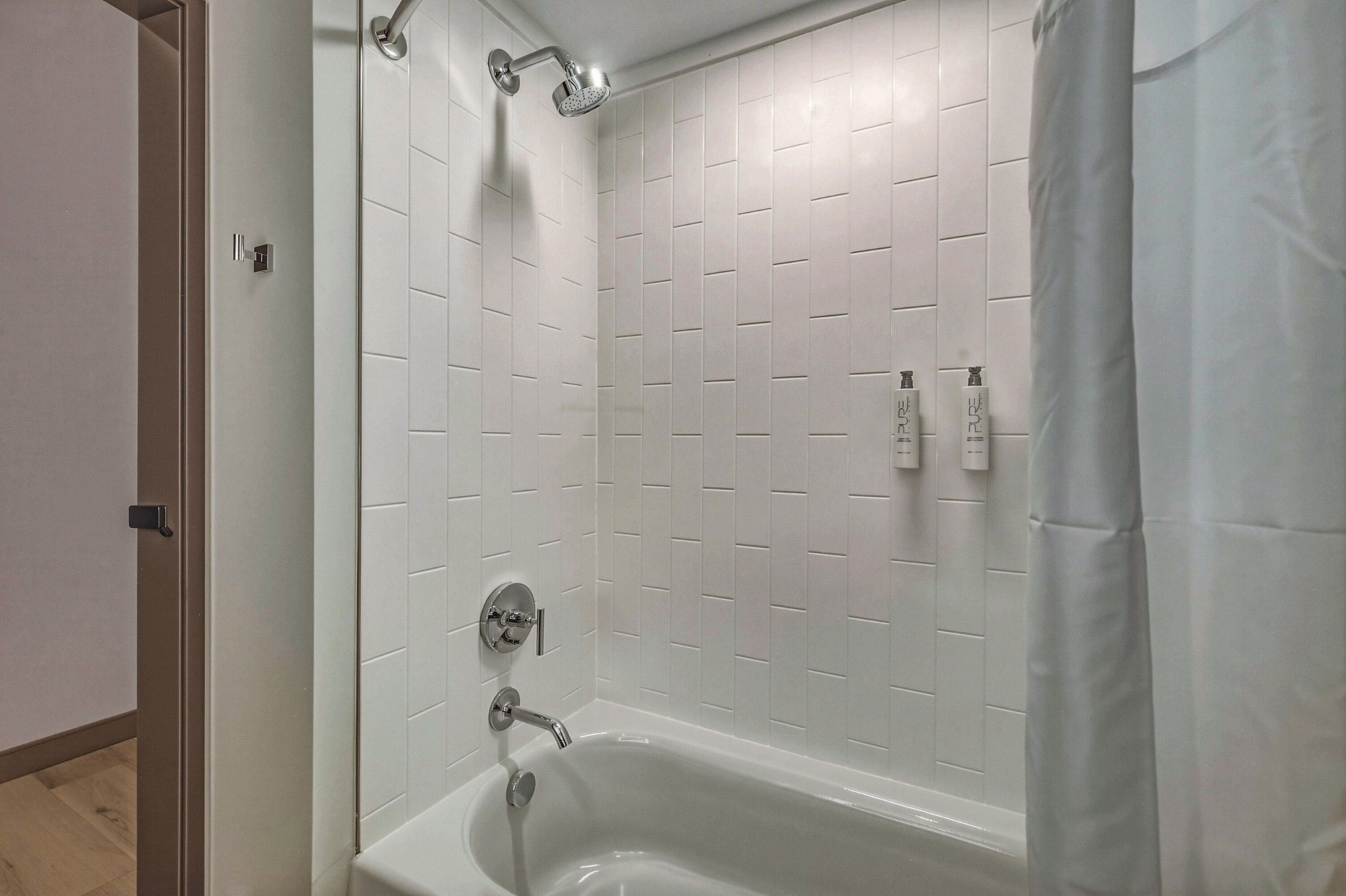Ein modernes Badezimmer mit Badewanne, Dusche und weißen Fliesen.