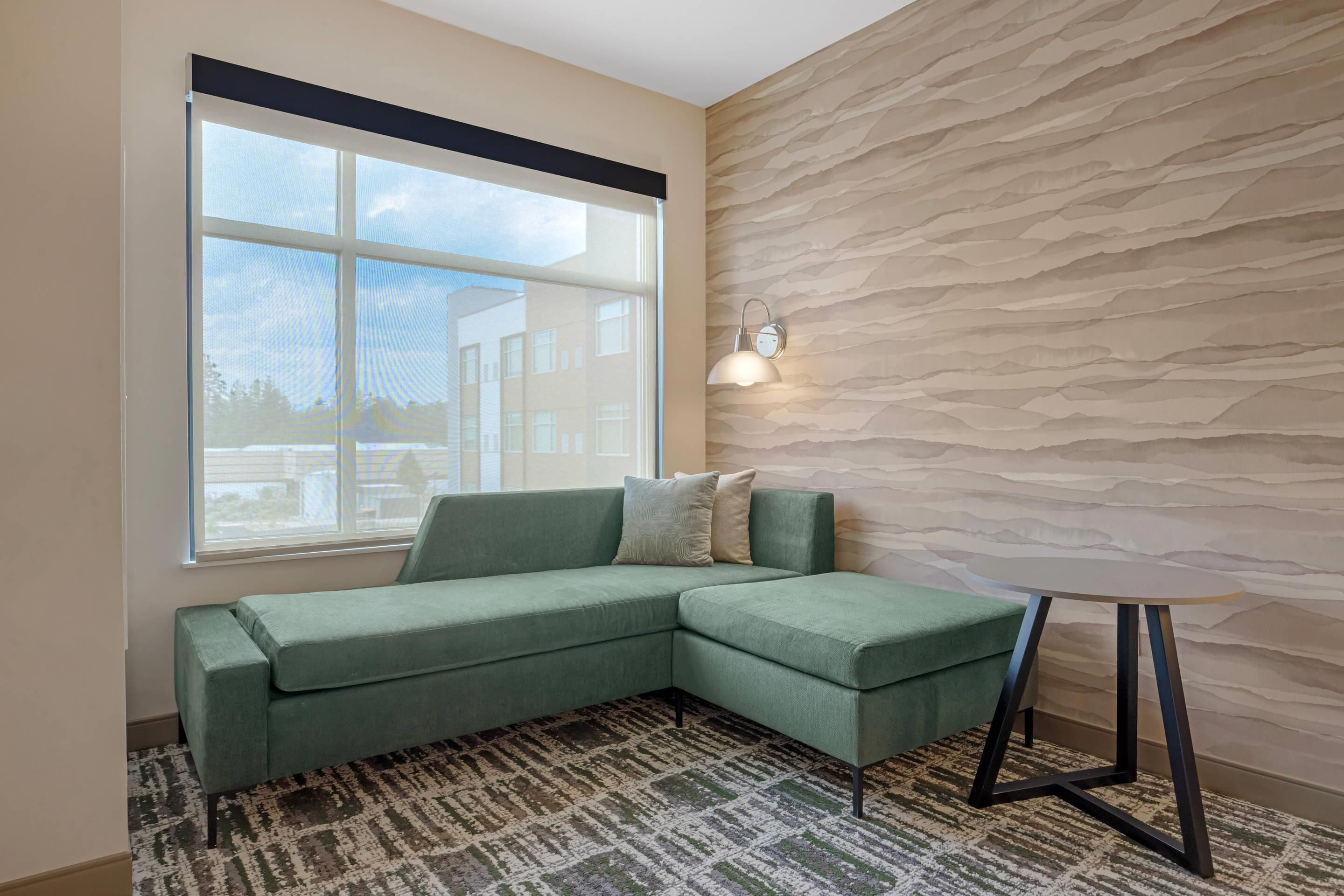 A modern living room with a sectional sofa, a patterned rug, a small round table, and a textured wall.