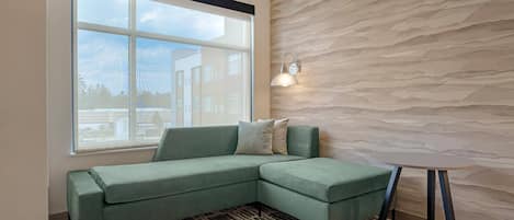 Una sala moderna con un sofá modular, una alfombra estampada, una mesita redonda y una pared con textura.
