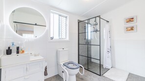 Uma casa de banho moderna com sanita, lavatório, espelho e cabine de duche.