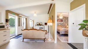 Ein geräumiges Hotelzimmer mit einem großen Bett, einer Sitzecke mit einer Couch, einem Esstisch und Blick auf den Garten.