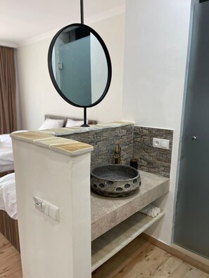A bathroom with a stone sink, a round mirror, and a white cabinet. - Relax in Nature. Cozy Georgian resort with pool, stunning Views &Tranquility (Tskaltubo)