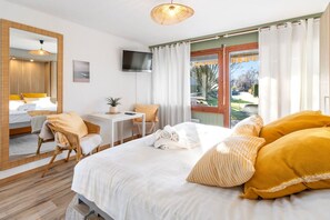 Een hotelkamer met een bed, een bureau, een stoel, een televisie en uitzicht op de omgeving.