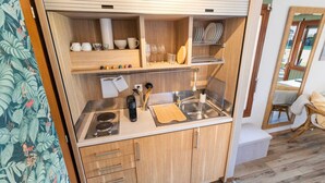 Une petite cuisine équipée comprenant un évier, une cuisinière et des placards de rangement.
