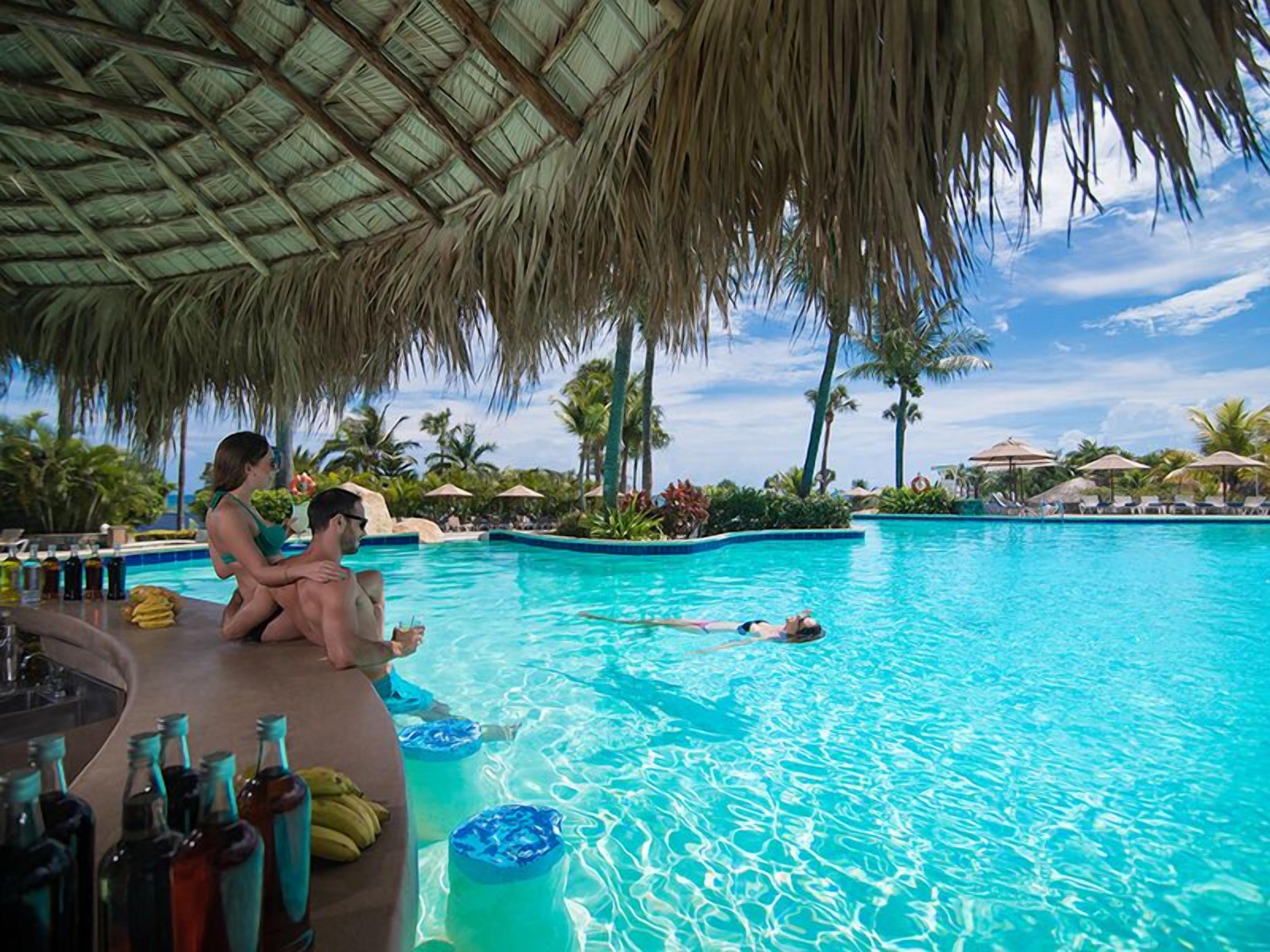 A swimming pool with a bar area and umbrellas.