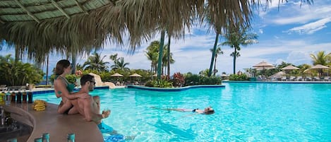 A swimming pool with a bar area and umbrellas.