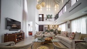 A spacious living area with a high ceiling, a glass coffee table, a sofa set, and a TV mounted on the wall. - Lifestyle Holiday Vacation Club (Puerto Plata)