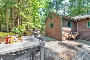 Eine Holzterrasse mit Esstisch, Grill und Gartenmöbeln.