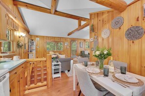 A wooden cabin interior with a dining area, kitchen, and living space.