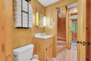 Ein Badezimmer aus Holz mit Toilette, Waschbecken und Handtuchhalter.