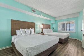 Une chambre d’hôtel avec deux lits, une table de chevet, une lampe, une fenêtre avec des stores et une bouche d’aération au plafond.