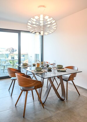 A modern dining area with a glass table, wooden chairs, and a unique ceiling light fixture. - Design Apartment Gottardo With Views Over Lugano (Massagno)