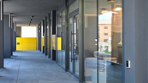 A corridor with glass doors, a tiled floor, and a view of a building outside. - Design Apartment Gottardo With Views Over Lugano (Massagno)