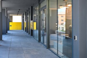 A corridor with glass doors, a tiled floor, and a view of a building outside. - Design Apartment Gottardo With Views Over Lugano (Massagno)