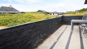 Ein Terrassenbereich mit Holzzaun, einem Betonweg und einem Tisch mit Stühlen.