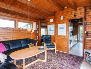 A cozy cabin interior with a wooden ceiling, a black leather sofa, a wooden table, and a patterned rug. - 5 Person Holiday Home in Fano (Fano)