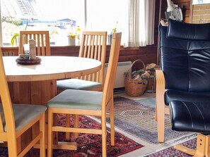 A wooden dining table with chairs, a black leather sofa, and a patterned rug. - 5 Person Holiday Home in Fano (Fano)