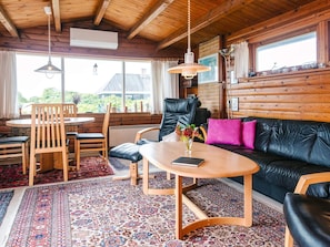 A cozy room with a wooden ceiling, a black leather sofa, a wooden coffee table, and a patterned rug. - 5 Person Holiday Home in Fano (Fano)